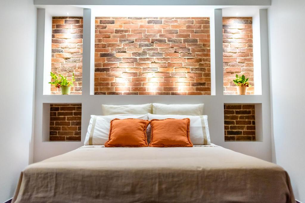 Suite room with illuminated exposed brick wall and orange cushions — Villa Maria Pia